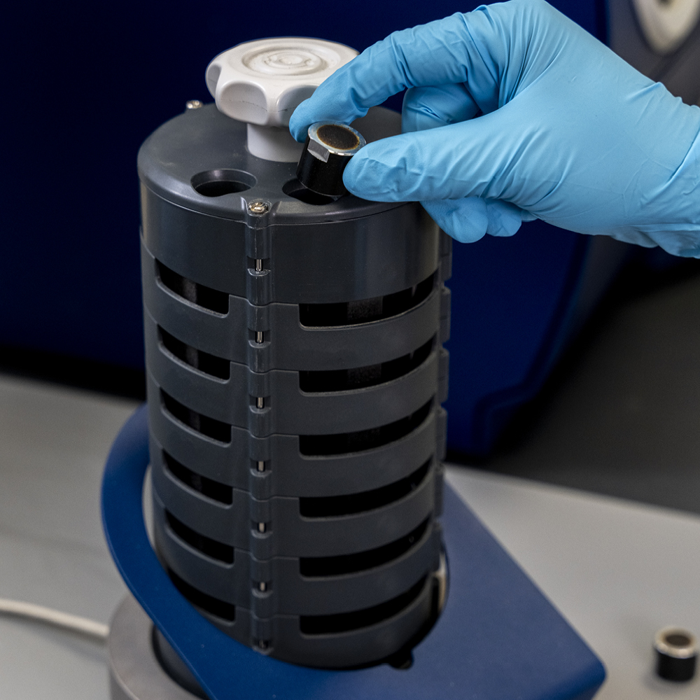 Gloved hand loading a sample cup into the Micral autosampler cassette